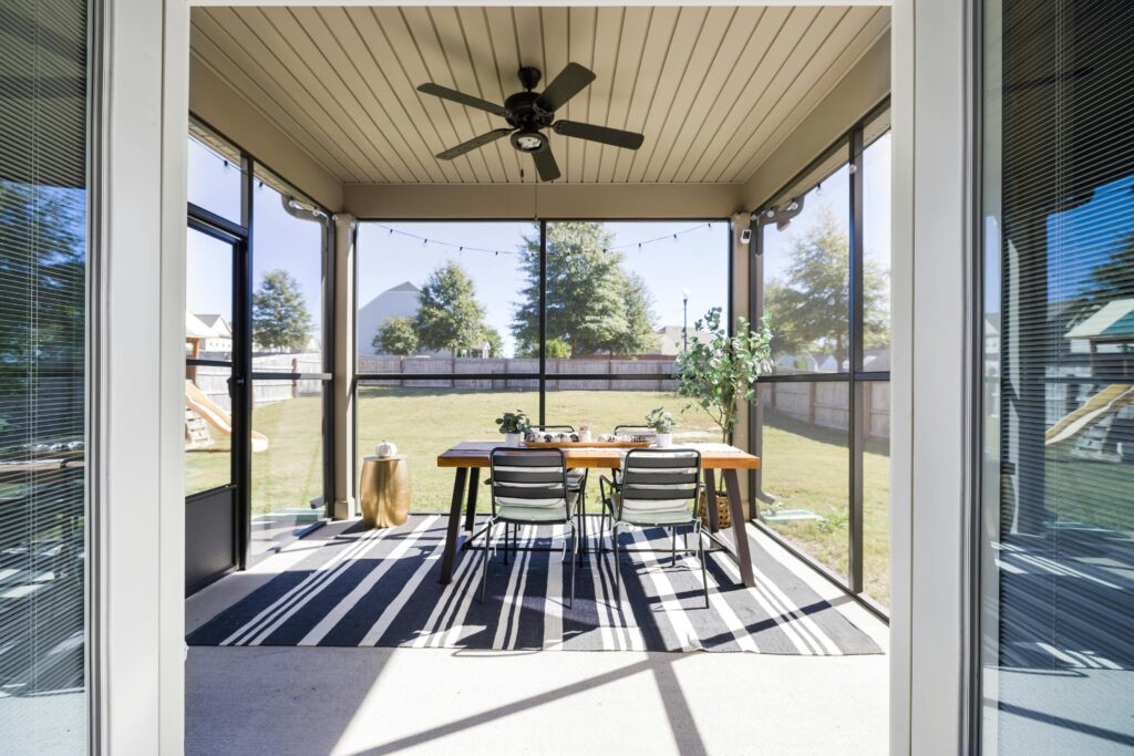 A bright and inviting terrace with dining table and chairs, overlooking a sunny garden.