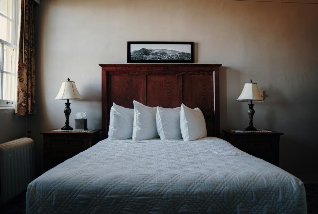 A beautifully arranged bedroom in Jerome, AZ, showcasing a wooden headboard, lamps, and a cozy bed.