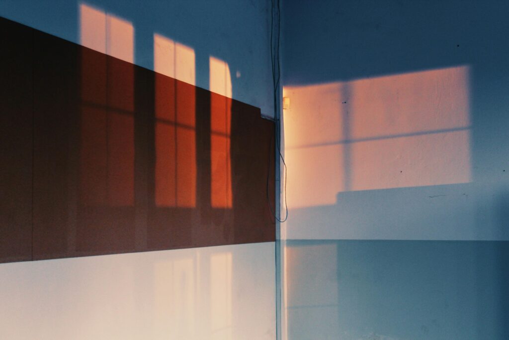 Artistic shadows of windows cast on a wall, creating a warm, intriguing pattern indoors.