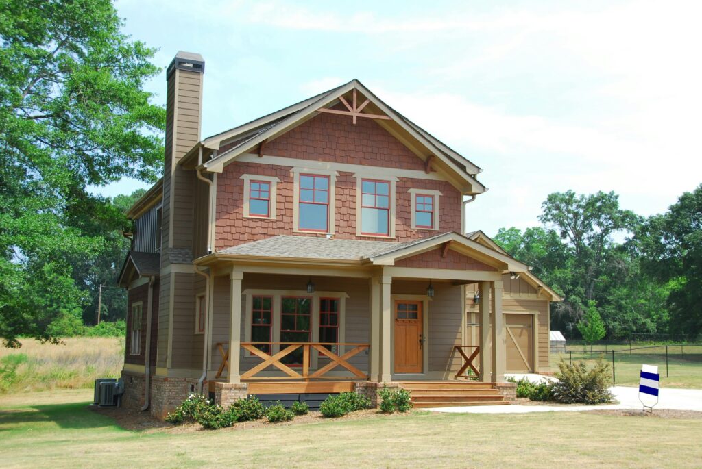 Charming single-family home with a porch, lawn, and trees, ideal for real estate use.