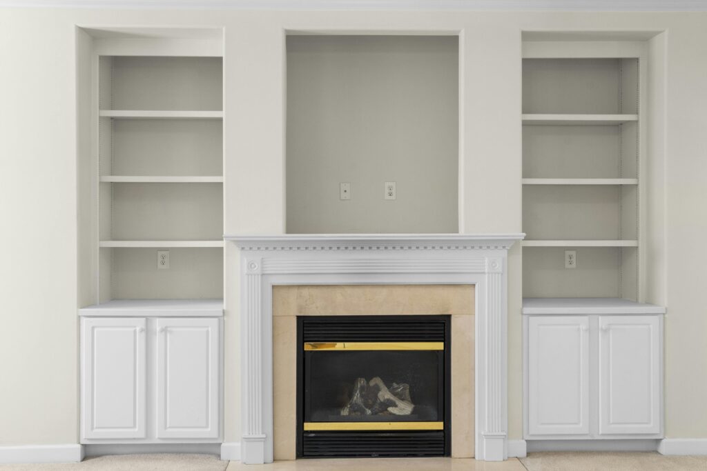 A luxurious white interior with built-in shelves and a central fireplace, perfect for modern homes.