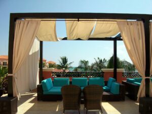 Elegant outdoor seating area on a sunlit rooftop overlooking the ocean.