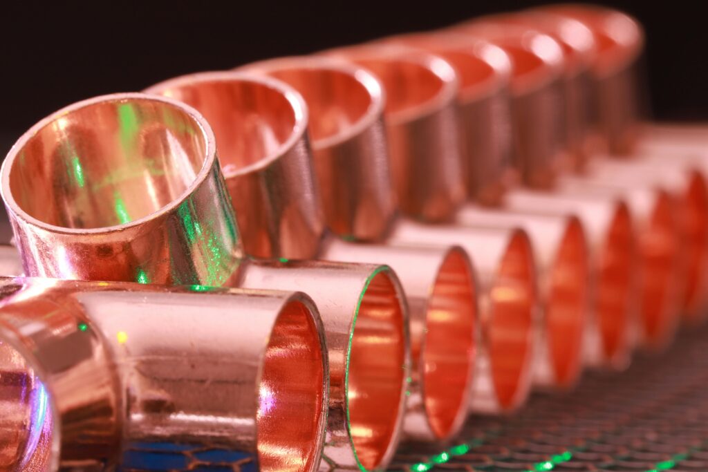 Copper plumbing fittings arranged in a row, showcasing metallic texture and industrial detail.
