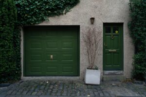 Elegant green door and garage in Edinburgh with climbing ivy creating a serene facade.