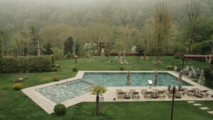 A peaceful outdoor pool surrounded by lush greenery and misty woods, perfect for relaxation.