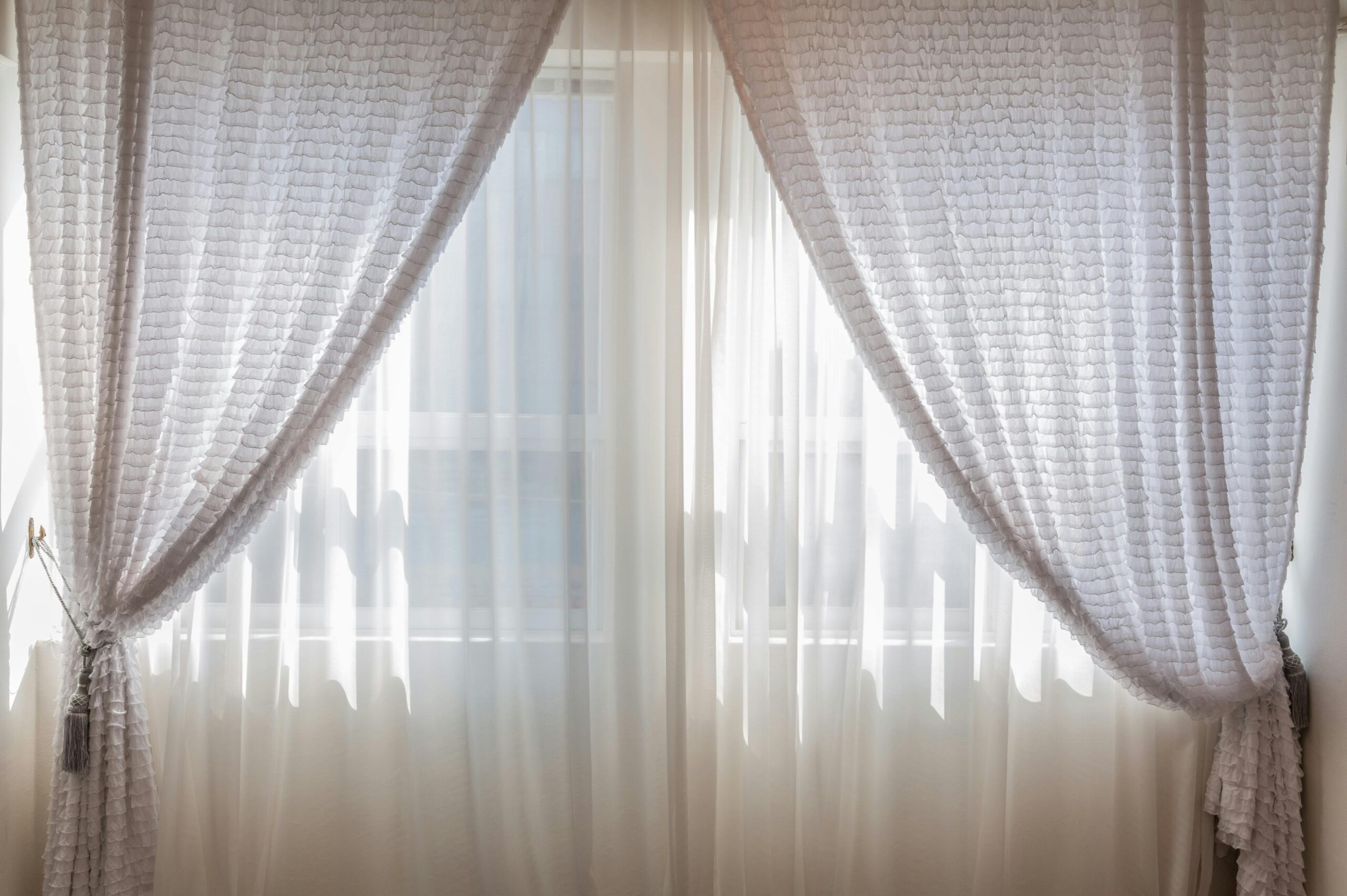 Sun shining through elegant white curtains in a cozy, modern interior setting.
