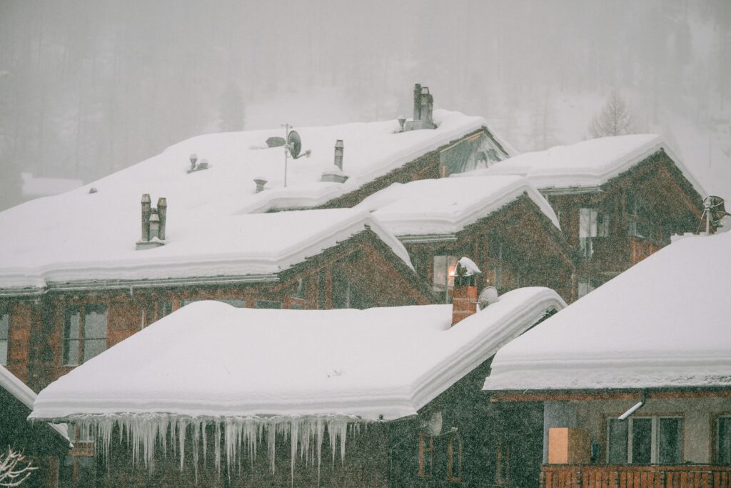 Charming wooden cabins with snowy roofs in a serene winter setting, creating a peaceful, rustic vibe.
