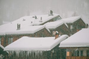 Charming wooden cabins with snowy roofs in a serene winter setting, creating a peaceful, rustic vibe.