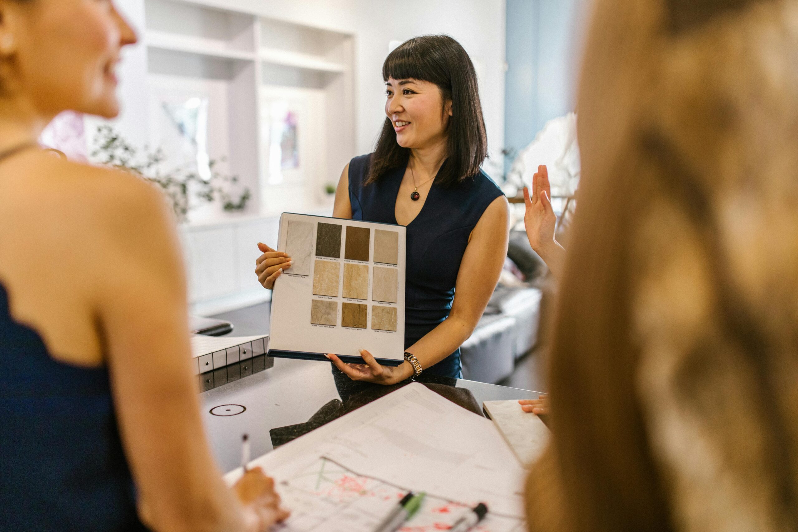 Interior designer presenting color swatches to clients in a modern workspace, fostering a creative atmosphere.