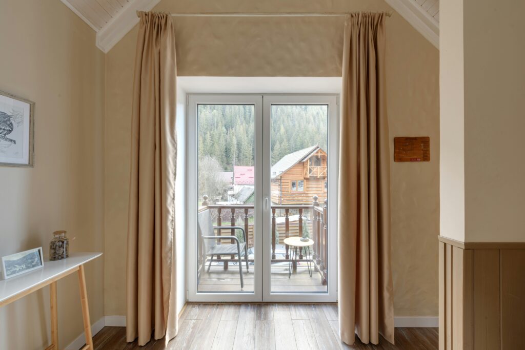 Interior shot of a cozy room with French doors opening to a scenic cabin view.