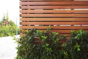 beautiful and functional privacy fence with horizontal wood slats and lush green shrubs along the base