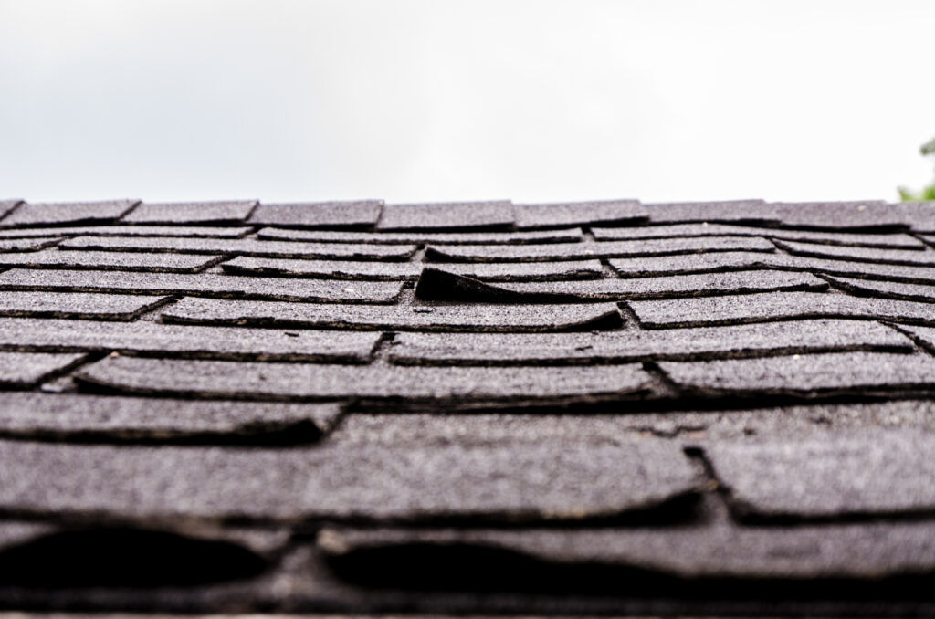 older roof showing weak points with curling shingles and worn flashing