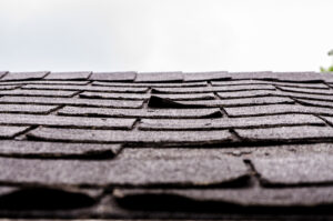 older roof showing weak points with curling shingles and worn flashing