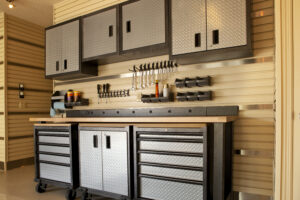 An inspirational and pristine garage workshop space with an epoxy floor, rolling tool cabinets, a heavy-duty timber workbench, and bright LED shop lights.