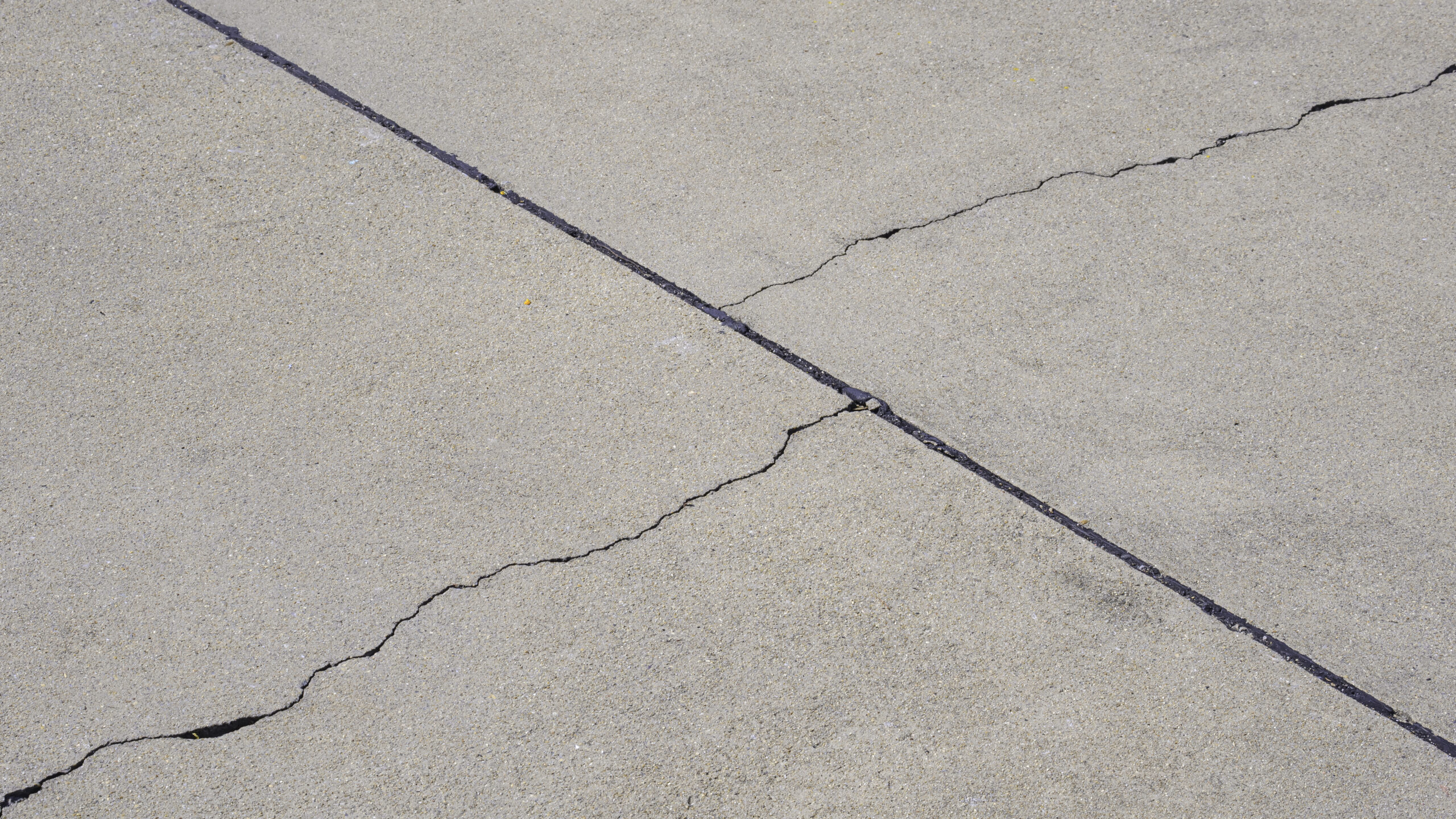 uneven concrete repair showing a sunken driveway slab with visible cracks and settling