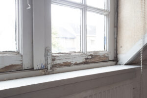 Close-up of a warped or damaged wooden window frame showing gaps and wear