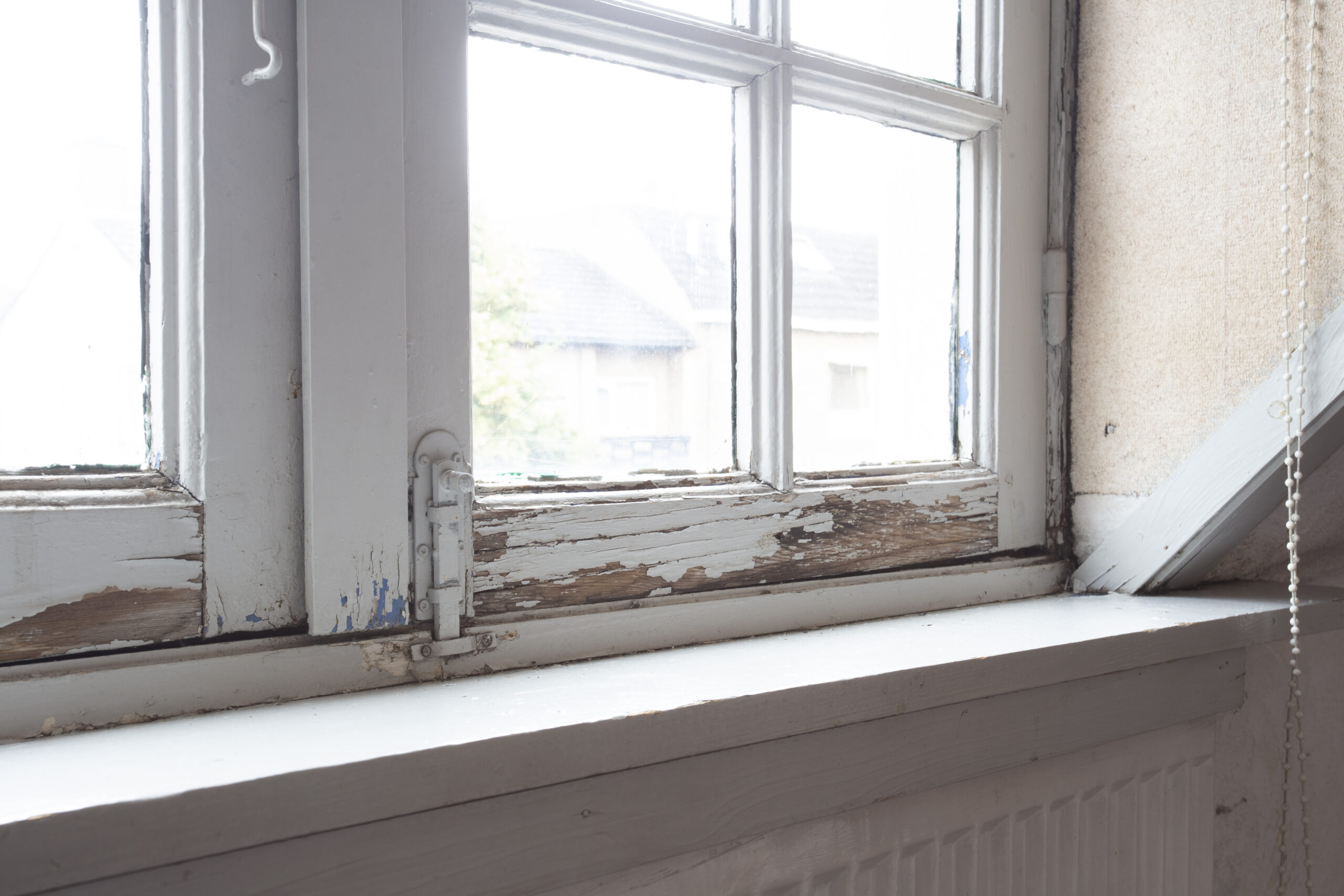 Close-up of a warped or damaged wooden window frame showing gaps and wear