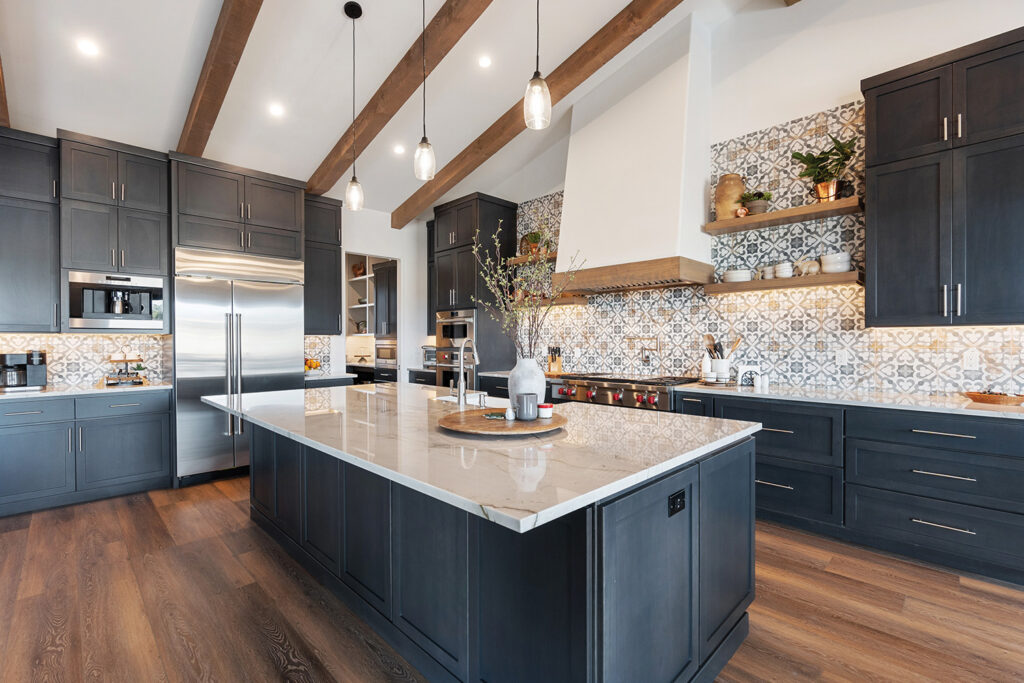 Modern kitchen with navy cabinets, a large marble island, patterned tile backsplash, open shelving and wood beams