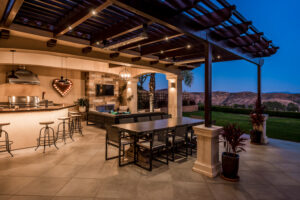 Warm outdoor lighting improves a backyard gathering space with a patio and landscaped surroundings.