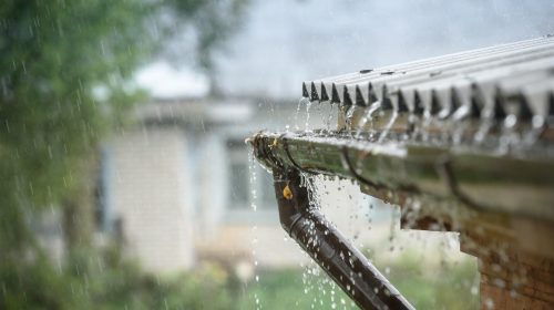 Residential roof and gutter system directing rainwater away from the home