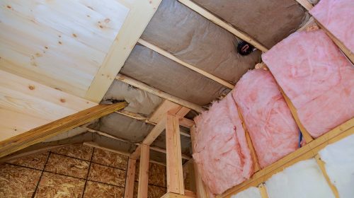 Attic loft insulation partly insulated wall covering view of layers of pink fiberglass barrier