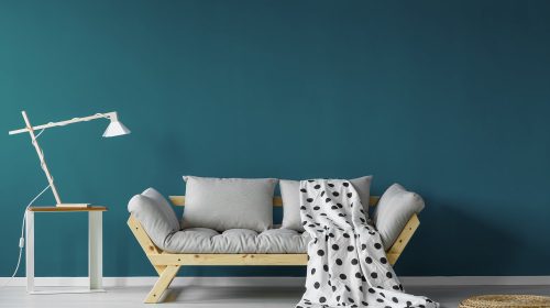 Teal painted living room with spotty blanket, modern lamp, and a small table