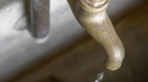 Water shortage concept. Old leaky dripping faucet.