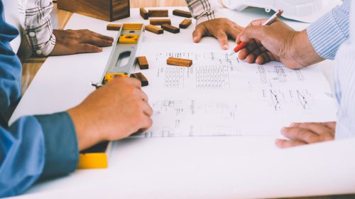 Team of engineers discussing architecture plan sketch at the construction site.
