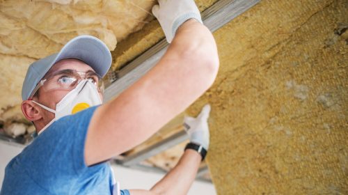 Mineral Insulation Installer. Caucasian Construction Worker Installing Mineral Wool Insulator.