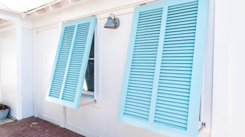 Pastel turquoise blue colorful hurricane window shutters closeup architecture open exterior of house in Florida beach home during sunny day, painted
