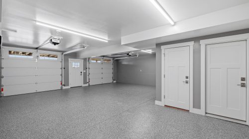 An interior view of an empty garage with a metallic surface floor and lighting