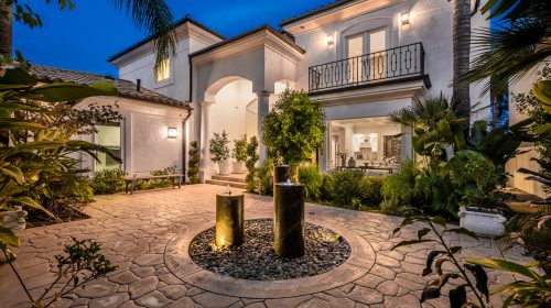 A modern house with a front yard fountain illuminated at night