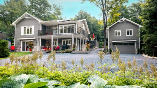 Luxurious gray and white property with detached garage located in Quebec, Canada during summer.