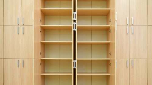 Empty wooden bookshelf with open doors and multiple shelves. Symmetrical storage furniture with metal handles in a modern interior. Storage and organization concept