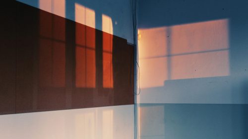 Artistic shadows of windows cast on a wall, creating a warm, intriguing pattern indoors.