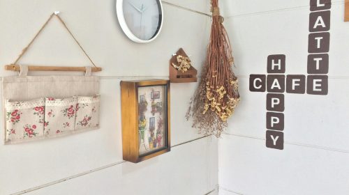 Modern café corner with minimalist decor, wall clock, and dried flowers.