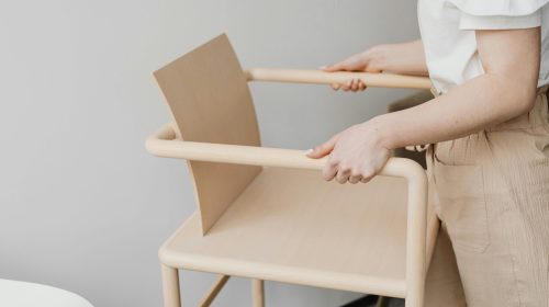 A woman holding a minimalist wooden chair, showcasing Scandinavian design